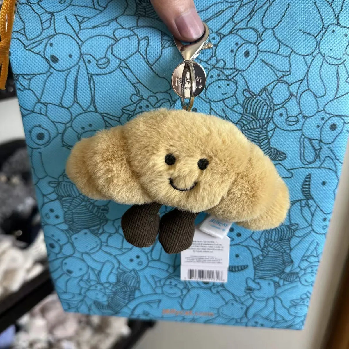FanzyMarket plush cotton cat keychain with two-tone croissant and cherry charms, soft and cute fashion accessory.
