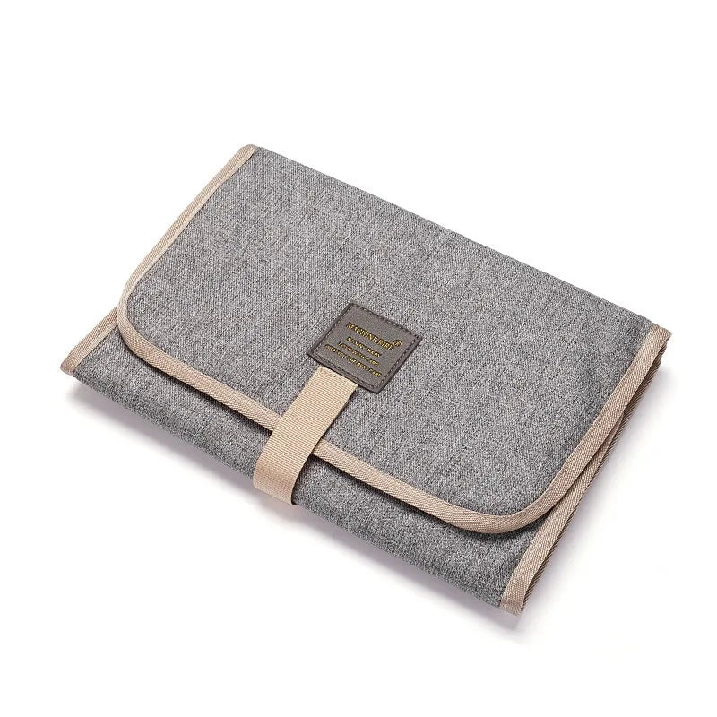 Light gray foldable waterproof baby changing pad by FanzyMarket, portable diaper mat for newborns and toddlers, made of Oxford fabric.