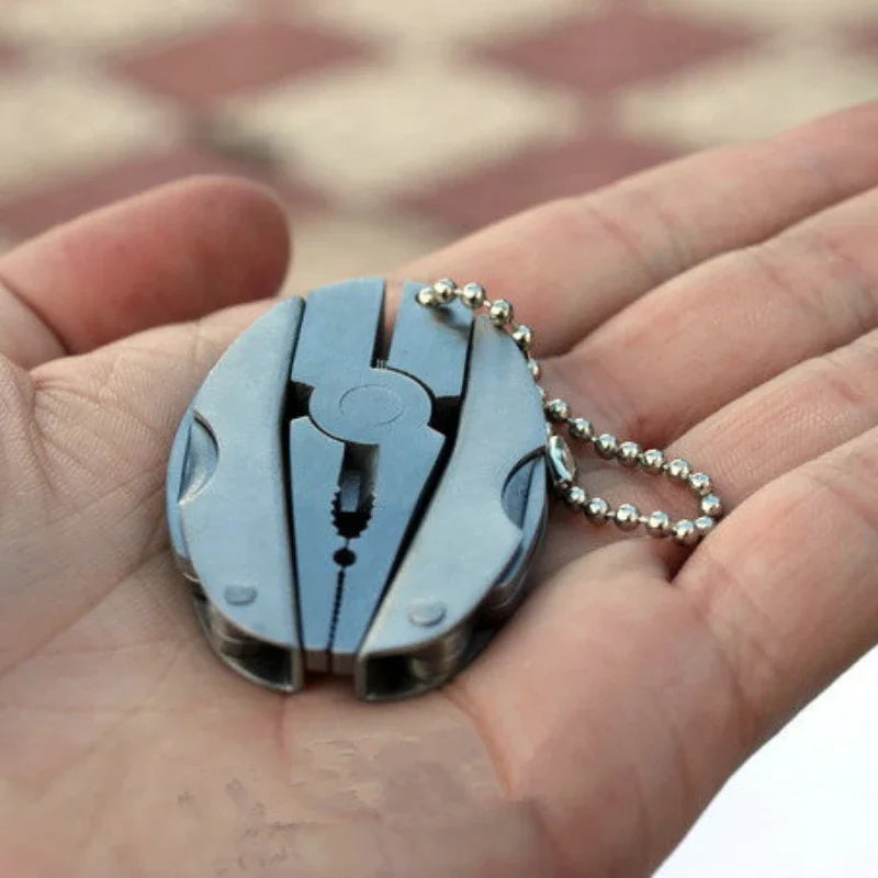 FanzyMarket compact steel multi-tool with folding pliers, knife, screwdriver, and keychain for camping and outdoor survival.