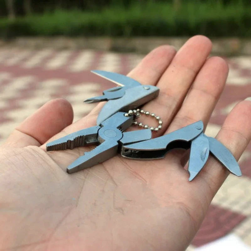 FanzyMarket compact steel multi-tool with folding pliers, knife, screwdriver, and keychain for camping and outdoor survival.